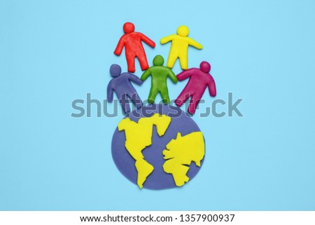 Plasticine multicolored cartoon people on globe. The use and depletion of the planet earth, overpopulation and population growth.