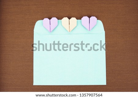 A blue envelope and an origami paper heart on a wooden texture background. Flat lay concept.