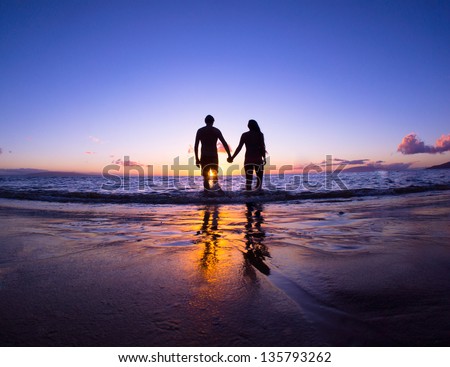 Romantic couple enjoying a beach walk at sunset Royalty-Free Stock Photo #135793262