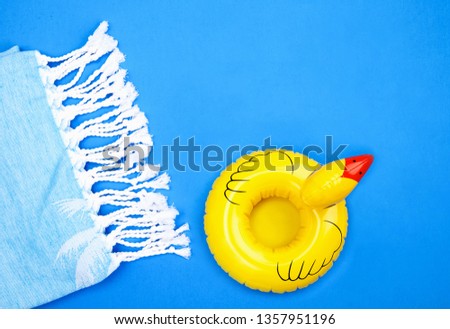 Inflatable Yellow Duck And Towel On Blue Background Royalty-Free Stock Photo #1357951196