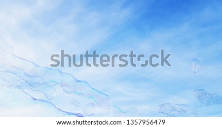 Blowing big soap bubbles in the air. Abstract shape, blue background.