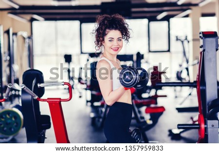 portrait of young woman making exercise with dumbbells at the gym 