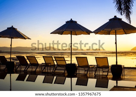 Silhouetted picture, the beautiful sunrise at the beach with bed and swimming pool.