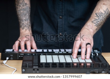 Cropped photo tattoo hands of DJ master man. He using professional instruments for creative music in black modern and sound studio with style interior