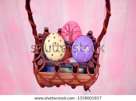 A girl holding a basket of colorful hand painted Easter eggs with pink distress wooden background, pastel colors eggs, each with a unique pattern.