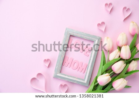 Happy mothers day concept. pink tulip flower with paper heart and Picture Frame with LOVE MOM text on pink pastel background.