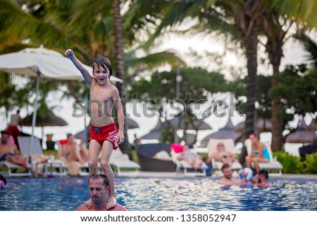 Cute preshool boy, jumping in the pool from his dad's shoulders