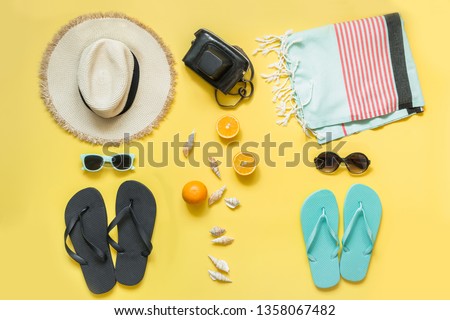 Beach accessories for two, straw beach sunhat,towel, sun glasses on yellow with space for text. Summer concept. Royalty-Free Stock Photo #1358067482