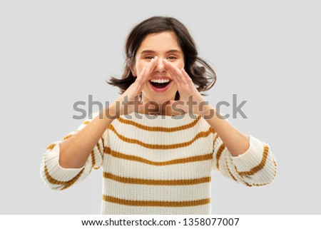 people concept - happy smiling young woman in striped pullover calling someone over grey background