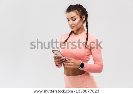 Picture of a beautiful young amazing strong sports fitness woman posing isolated over white wall background using mobile phone.
