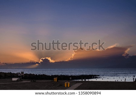 Sunset on the beach with the sun hidden among the clouds