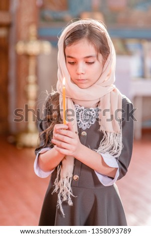 Sad girl with a candle in the church