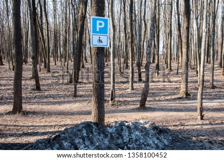 Disabled parking sign in before woods in the background