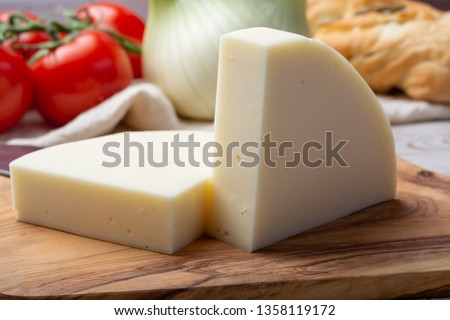 Italian cheese, Provolone dolce cow cheese from Cremona served with olive bread and tomatoes close up Royalty-Free Stock Photo #1358119172