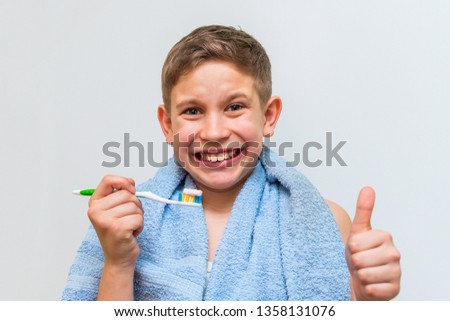 joyful teen boy brushes his teeth and shows OK sign