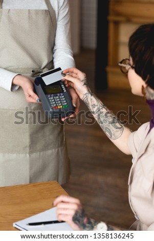 selective focus of businesswoman holding credit card near waitress with payment terminal