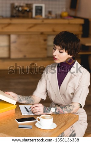 fashionable, concentrated businesswoman sitting at table in coffee shop