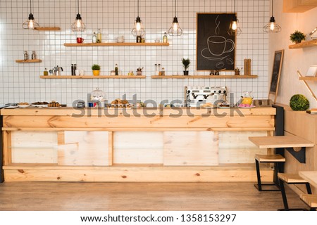 interior of cafeteria with wooden bar counter, shelves and board with drawn coffee cup Royalty-Free Stock Photo #1358153297