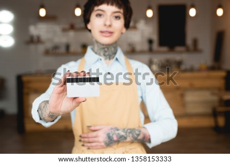 selective focus of waitress holding credit card and looking at camera