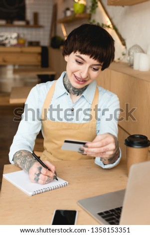 smiling waitress looking at credit card and writing in notebook