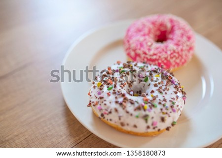 Donuts on a wooden background and space for text.  Party food concept with copy space. Picture of assorted donuts in a box with chocolate frosted, pink glazed and sprinkles donuts. 