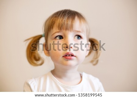 cute child girl with two pigtails and quiff of blonde hair closeup portrait