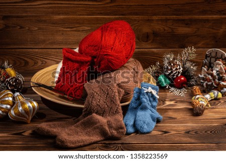 colored balls of thread, multi-colored knitted socks and Christmas tree decorations on a wooden background
