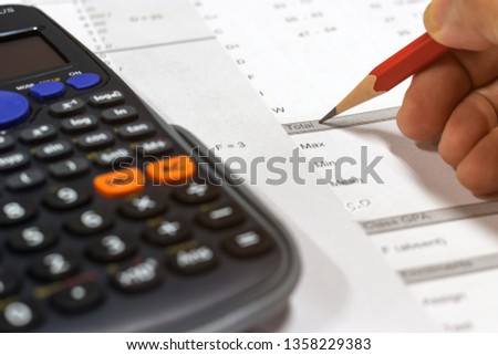 Hand holding pencil and calculator on paper of final grade for each course at the end of semester. The number of grade points a student earned in a given period of time. Grading in education concept.