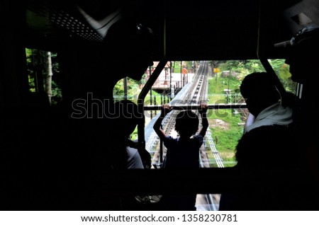 Image from inside a hill train with silhouette of tourists and clear view or the railway