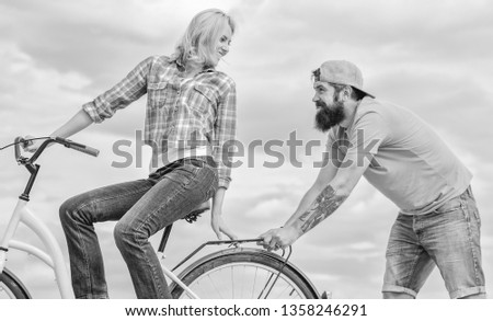 Woman rides bicycle sky background. Service and assistance. Man helps keep balance ride bike. Girl cycling while man support her. Support helps believe in yourself. Support and friendship.