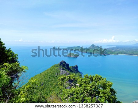 The view of the sea from the mountain top corner consists of a blue sea,  green island and bright blue sky.
