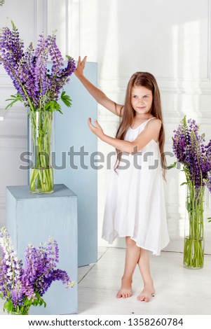 Portrait of the lovely little girl with  flowers. The girl laughs and plays