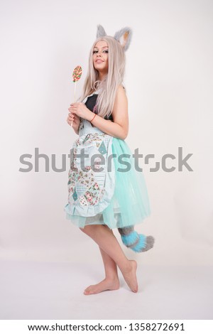 charming caucasian kitty teenage girl in kitchen apron with colorful Lollipop on white Studio background