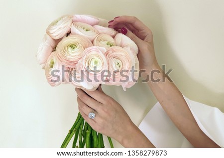 Woman in white dress with beautiful sleeves, flower bouquet and big engagement diamond ring