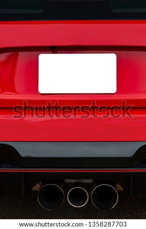 Vertical shot of a blank white license plate on the back of a red car.