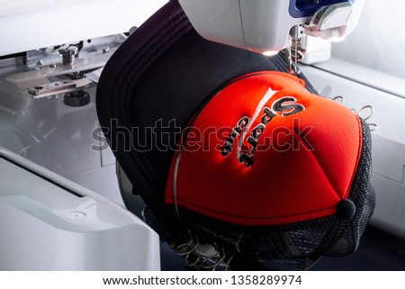 Close up picture of sport cap red and black color on the hoop of embroidery machine