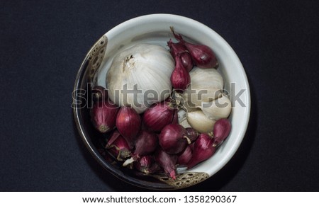 bowl with onions and garlic on a bluish-gray background in a white-brown bowl