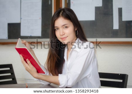Portrait of thai adult working women white shirt reading red book