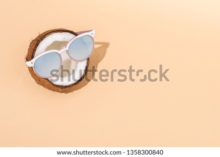 Half a coconut in sunglasses on yellow background. The concept of relaxation, summer mood, copy space.