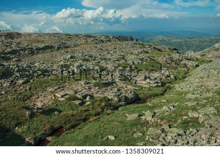 Hilly landscape of green ravine with rocks covered by moss and lichens, on sunny day at the highlands of Serra da Estrela. The highest mountain range in continental Portugal, with astonishing scenery.