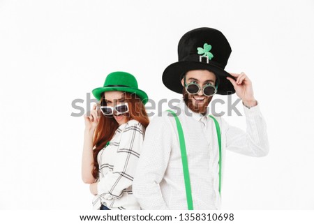 Happy young couple wearing costumes, celebrating St.Patrick 's Day isolated over white background, having fun together, posing with sunglasses