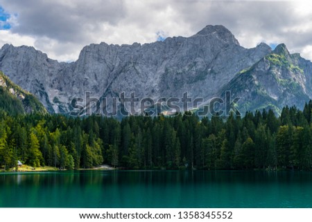 Scenic alpine landscape: mount Mangart hanging over beautiful alpine lake of fusine, Friuli Venezia Giulia region, Italy 