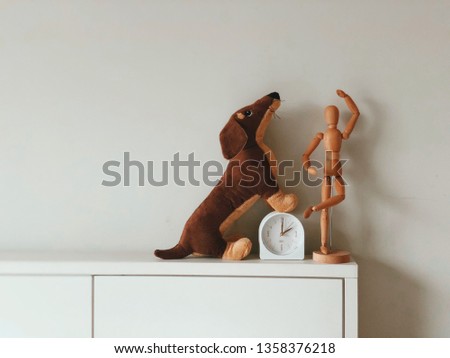 the Dachshund dog doll stands on the white bed head