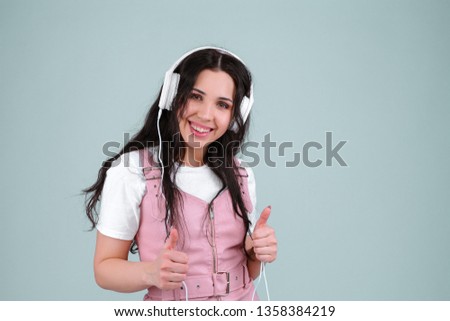 Gorgeous brunette lady in pink leather dress listen for her favourite music with white headphones. Audio book or internet radio podcast broadcast listen. enjoy and relax music. Thumb up gesture.