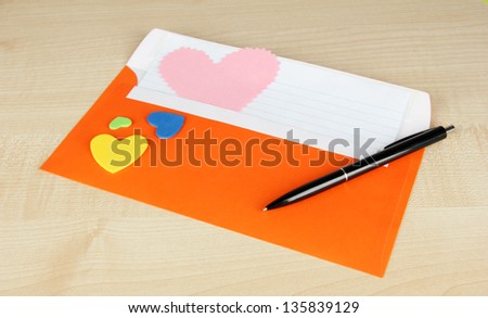 Note in envelope with pen on wooden background