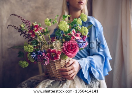 Young woman holding basket with flowers. Vintage, romantic concept.