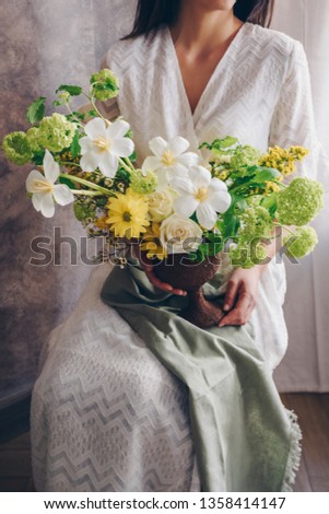 Young woman in a white dress holding vase with flowers. Vintage, romantic concept.