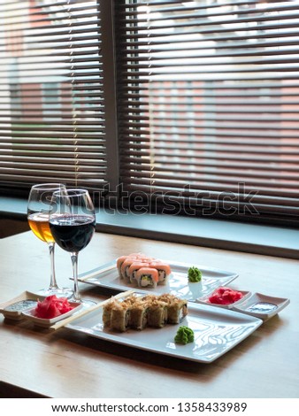 
on the table a glass of wine and sushi, two kinds of sushi