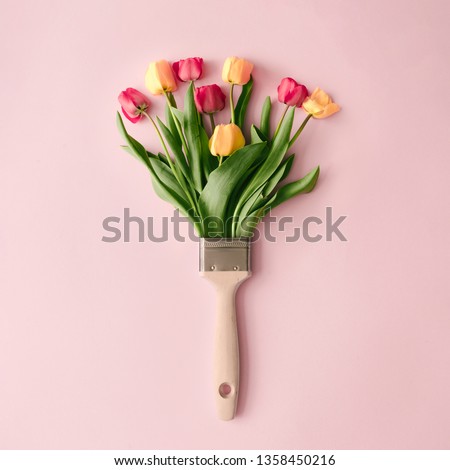 Creative spring concept made with paint brush and colorful tulip flowers on pastel pink background. Minimal nature flat lay. Royalty-Free Stock Photo #1358450216