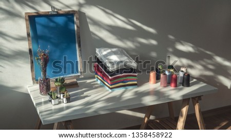 Stack of clothes on table, Fresh folded cotton clothing, colorful thread on table, Silk screen frame